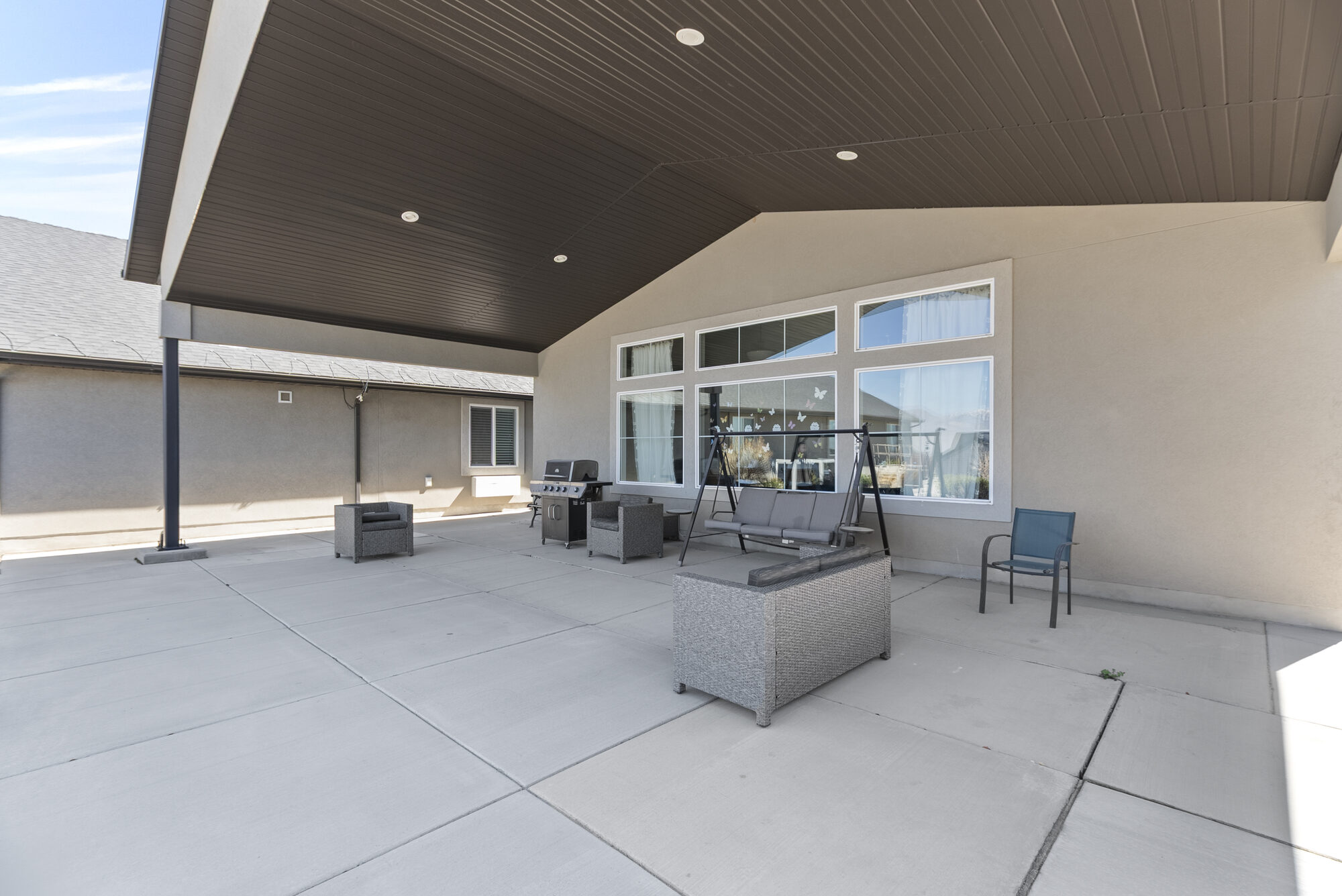 Covered patio with seating, a porch swing, and a grill for residents