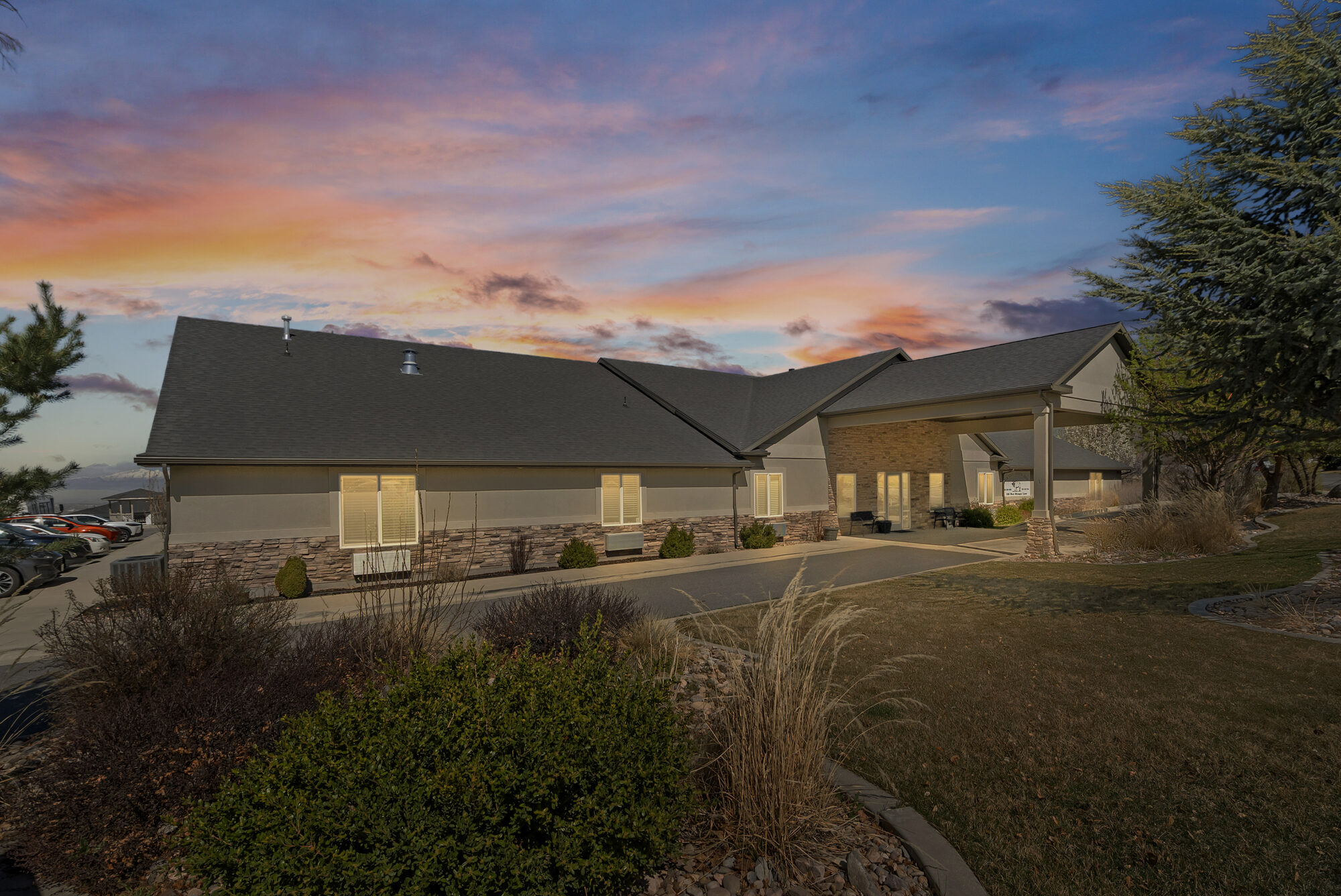 Elk Ridge Assisted Living at sunset, with a pink and purple sky over the front entrance